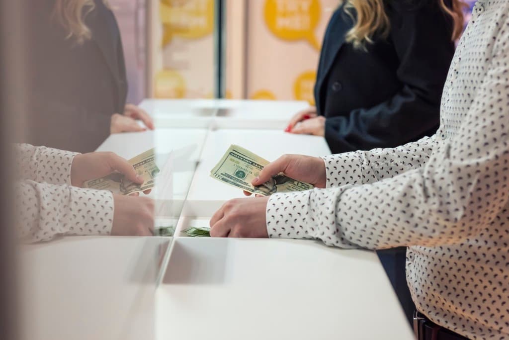 A person passing money to a bank teller